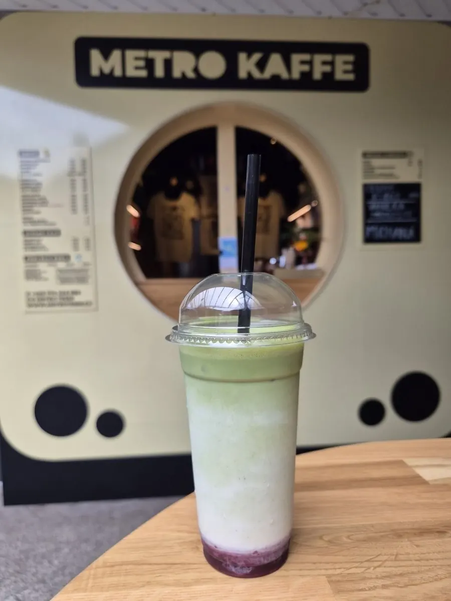 Ledová matcha v kelímku před okénkem Metro Kaffe